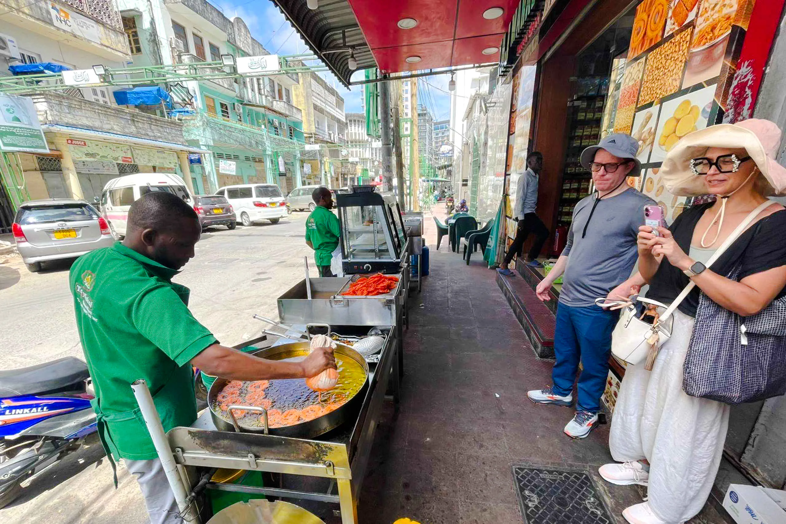 Street vendor cooking food in Zanzibar with tourists observing.