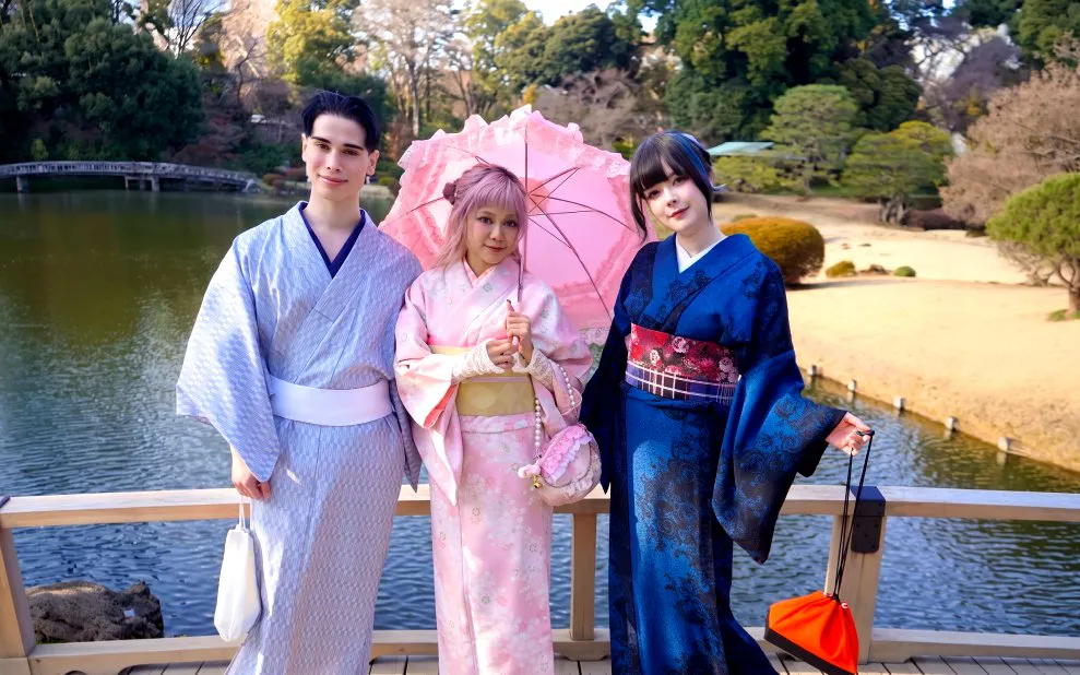 Visitors in kimonos at Shinjuku Gyoen National Garden, Tokyo, standing by a pond.