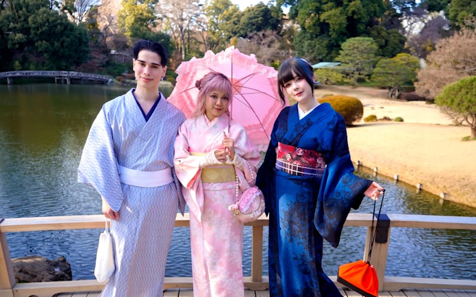 Visitors in kimonos at Shinjuku Gyoen National Garden, Tokyo, standing by a pond.