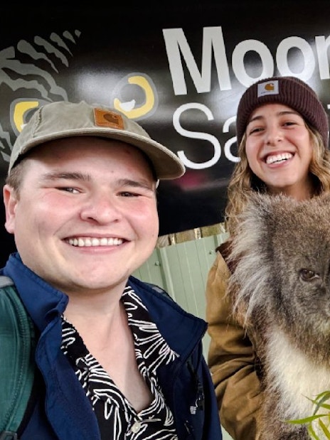 Visitors with a koala at Moonlit Sanctuary, Australia.