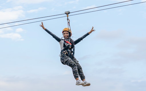 Woman ziplining at Hatta Wadi against a clear sky.