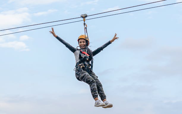 Woman ziplining at Hatta Wadi against a clear sky.