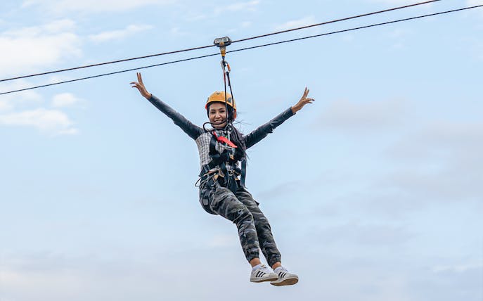 Woman ziplining at Hatta Wadi against a clear sky.