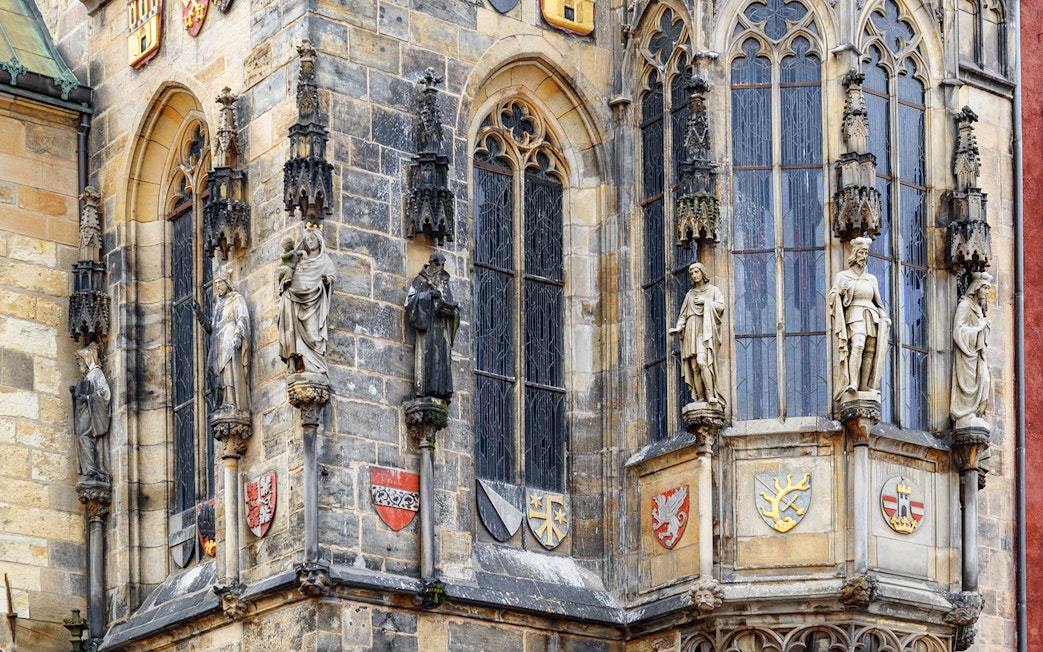 Statues and coats of arms on Prague's medieval building facade.