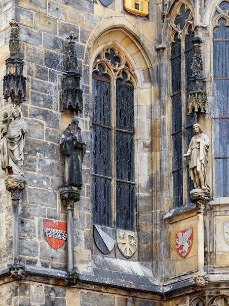 Statues and coats of arms on Prague's medieval building facade.