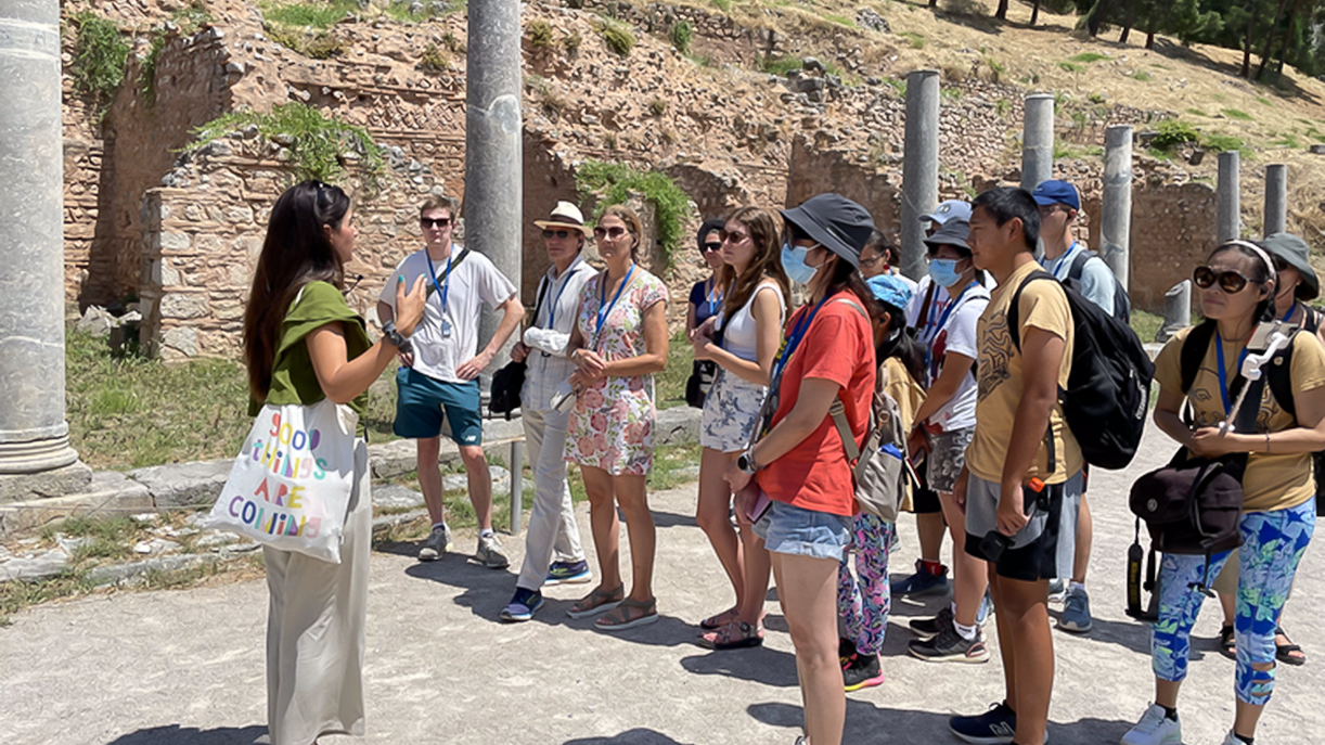 Tour guide explaining ruins to tourists during Day Trip to Delphi and Arachova.