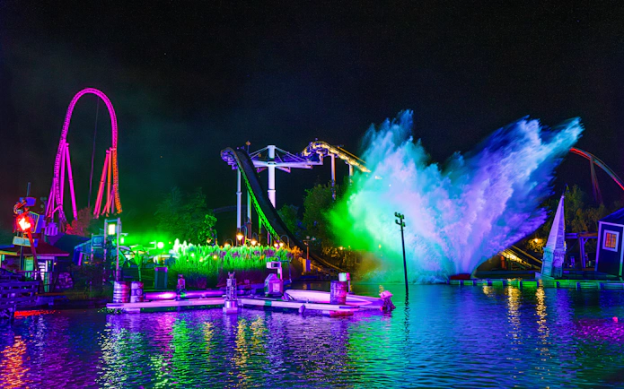 Thorpe Park Fright Nights water ride with colorful lights and splash at night.