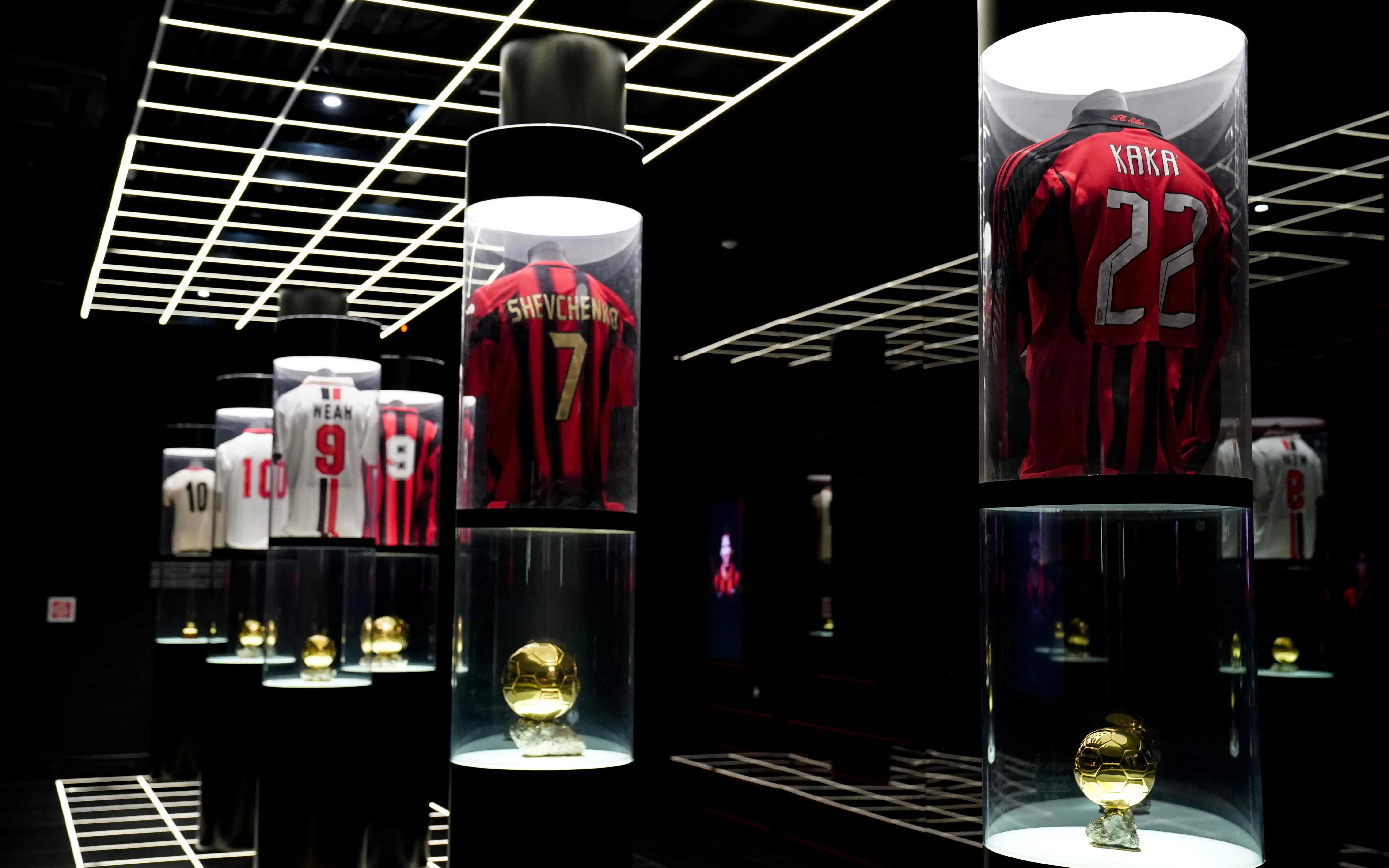 Casa Milan Museum exhibit featuring iconic football jerseys and trophies, Italy.