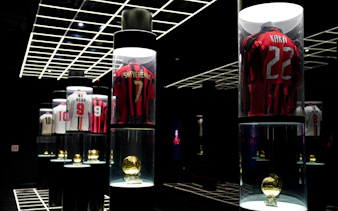 Casa Milan Museum exhibit featuring iconic football jerseys and trophies, Italy.