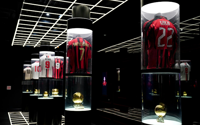 Casa Milan Museum exhibit featuring iconic football jerseys and trophies, Italy.
