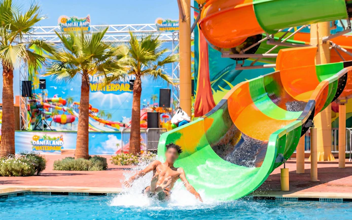 Person sliding down colorful water slide at Agadir Aqua Park.