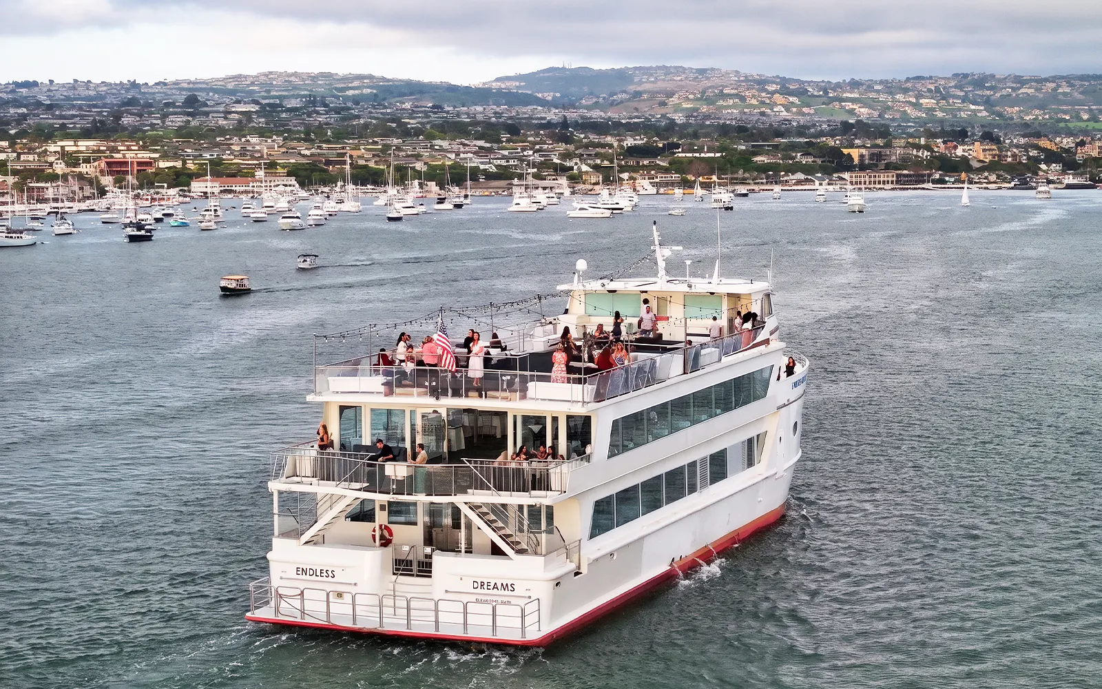 Cruise ship with guests on deck in Newport Beach harbor.