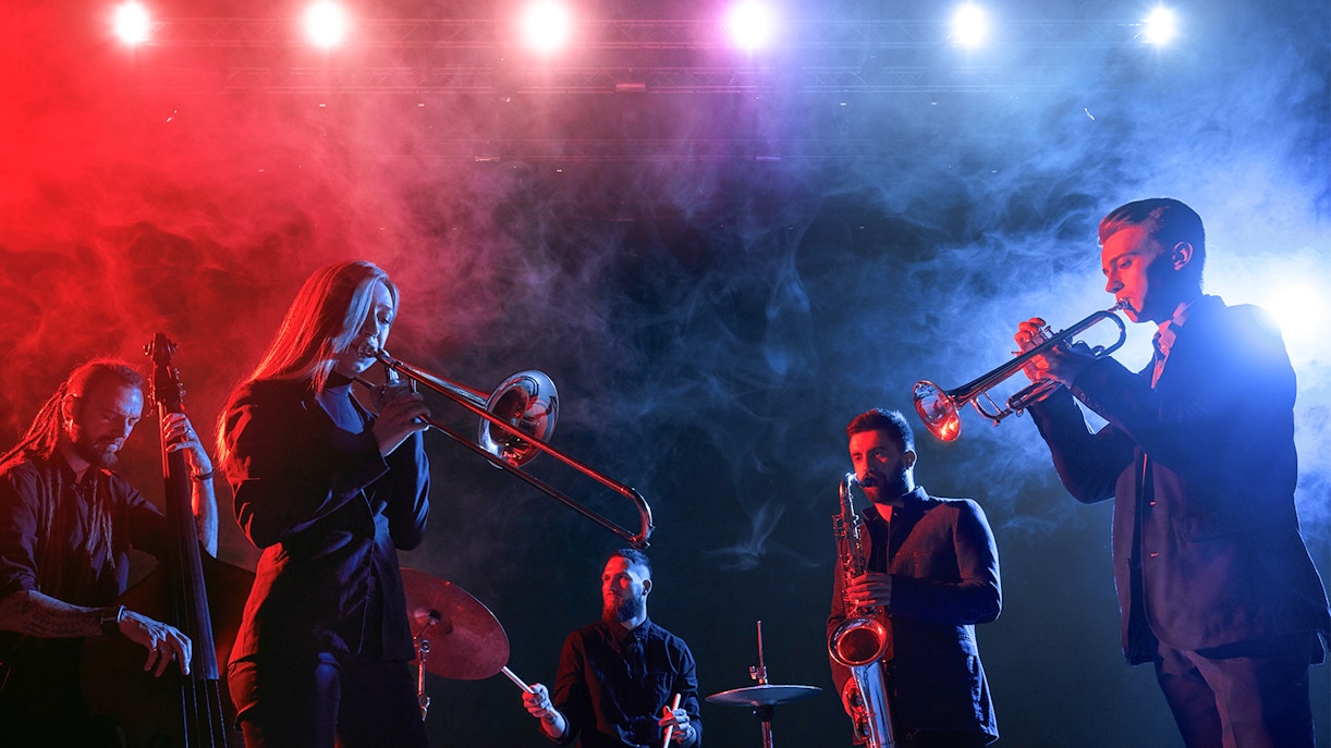 Jazz band performing on stage with colorful lights and smoke effects.