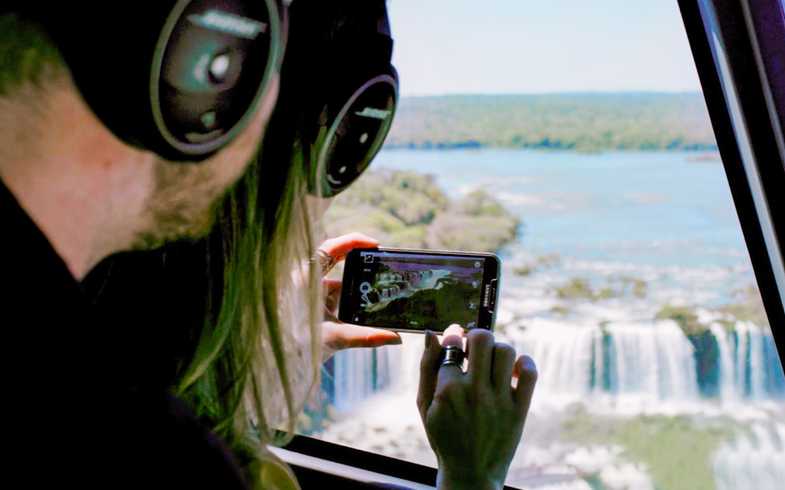 Helicopter view of Iguazu Falls cascading between lush rainforest, Argentina-Brazil border.