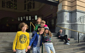 Children on steps outside Flinders Street Station, Melbourne, part of the self-guided city exploration game.