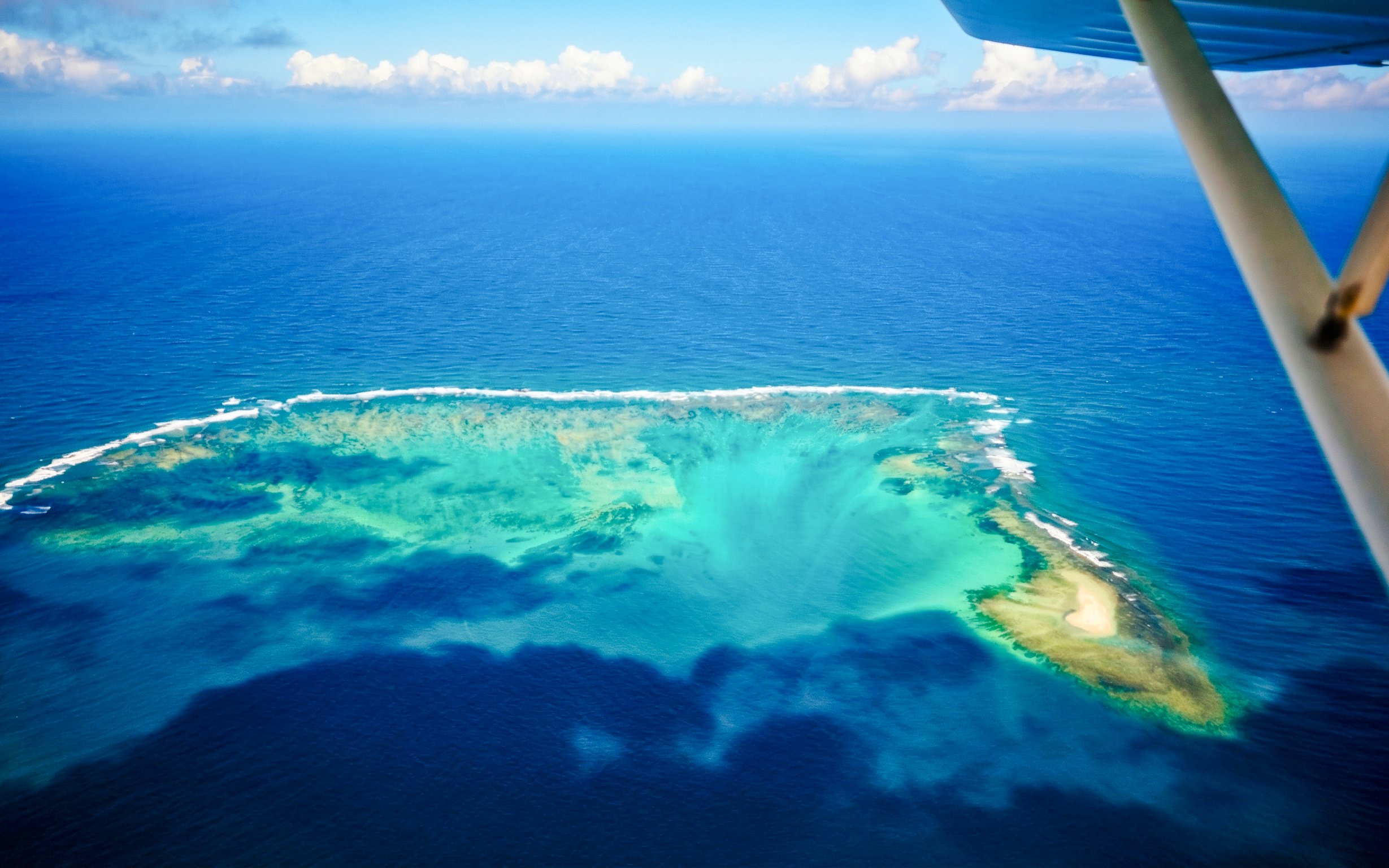 Aerial view of the underwater waterfall illusion near Mauritius on a seaplane tour.