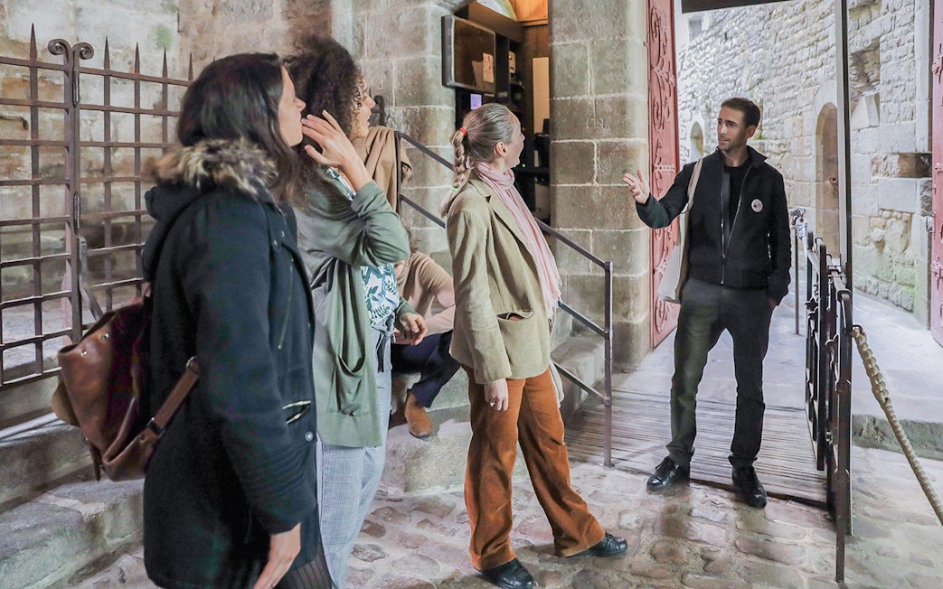 Visitors listening to a guide at Mont Saint-Michel entrance.