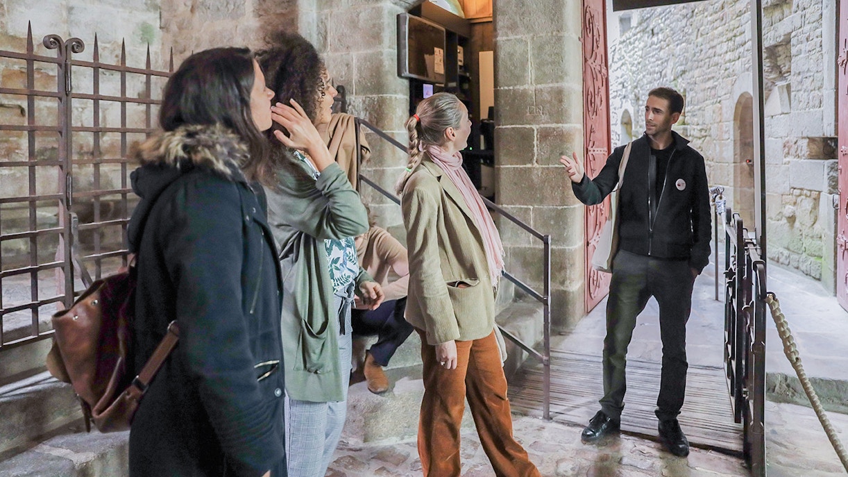 Visitors listening to a guide at Mont Saint-Michel entrance.