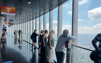 Visitors observing Shanghai skyline from Shanghai Tower observation deck.