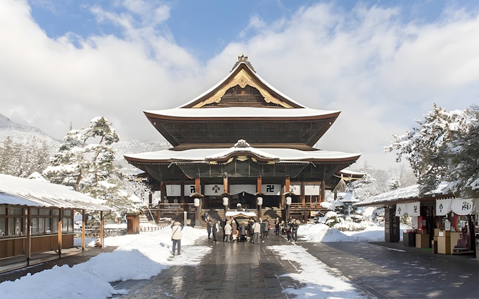 Zenko-ji Temple in Nagano covered in snow with visitors exploring the grounds.