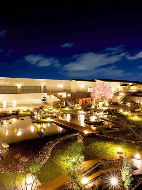 Solaniwa Onsen garden at night with illuminated pathways and pond in Osaka, Japan.