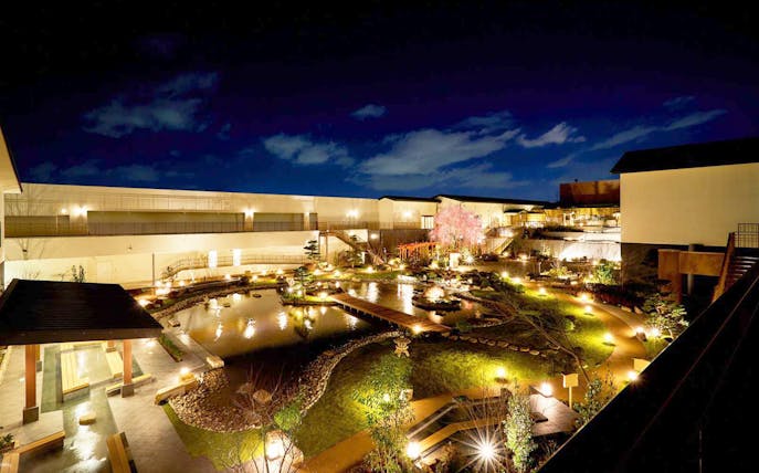 Solaniwa Onsen garden at night with illuminated pathways and pond in Osaka, Japan.