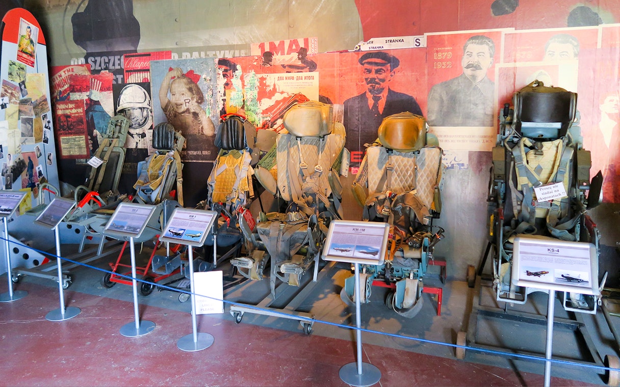 Ejection seats display at Polish Museum of Aviation with historical posters in the background.