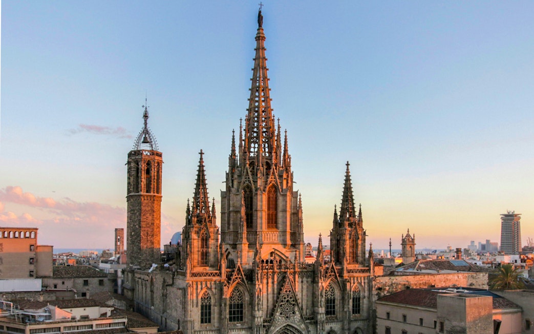 Barcelona Cathedral at sunset with cityscape in the background.