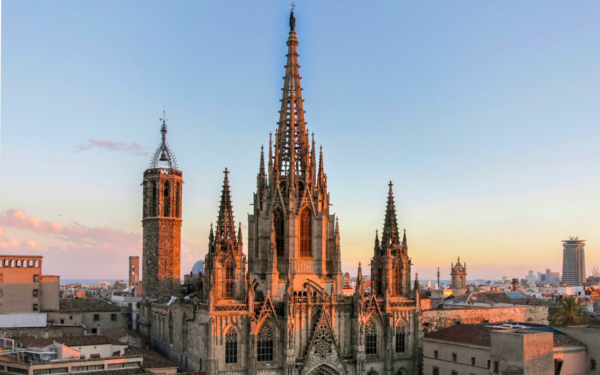 Barcelona Cathedral at sunset with cityscape in the background.