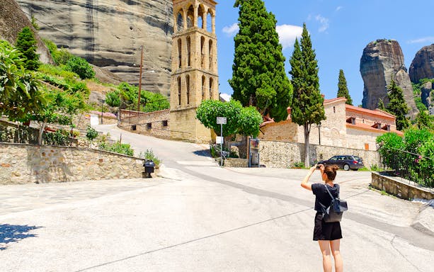 Tourist photographing Byzantine Church bell tower in Greece.