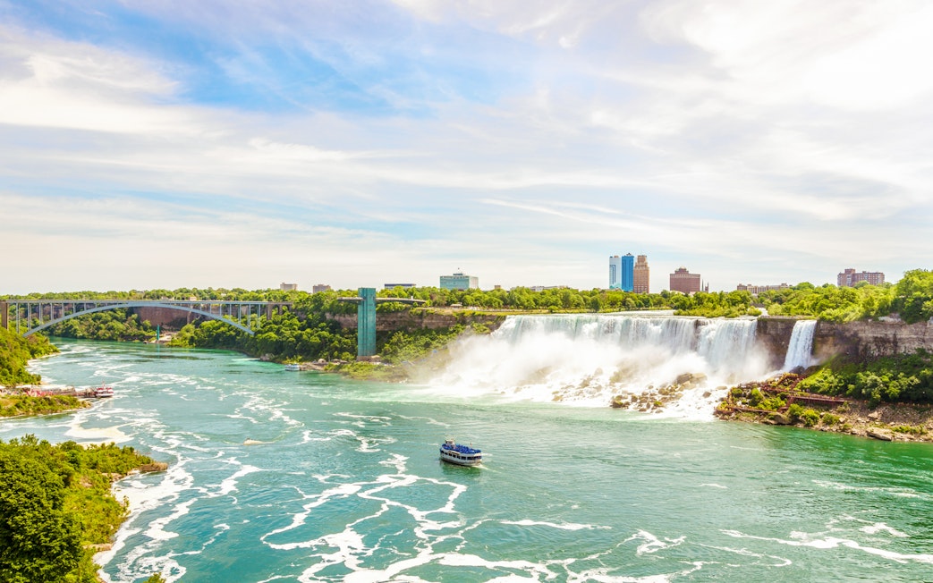 Rainbow International Bridge over Niagara River with boat and falls in view.