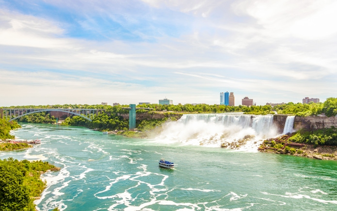 Rainbow International Bridge over Niagara River with boat and falls in view.