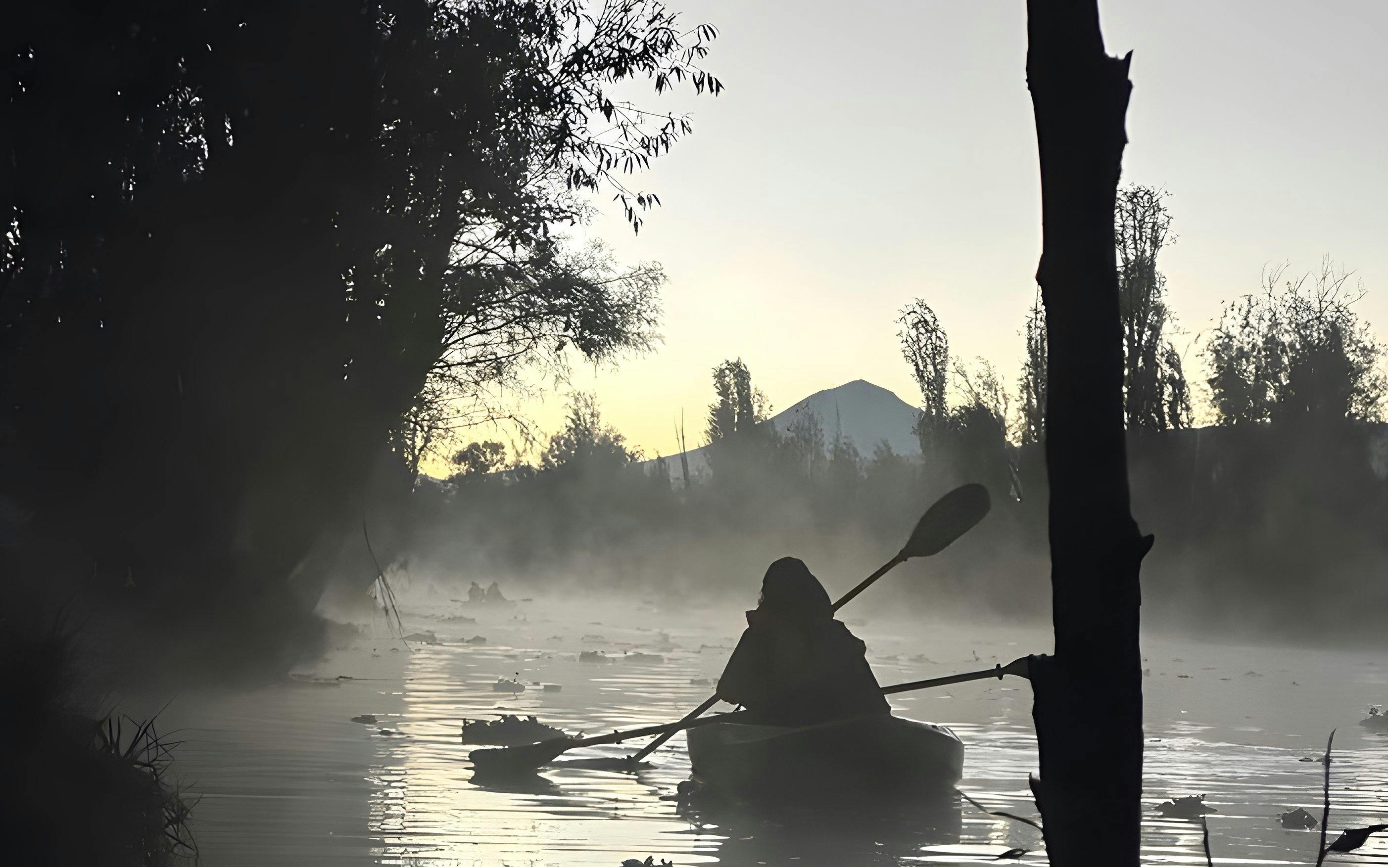 Kayaker paddling at sunrise in the misty canals of Xochimilco.