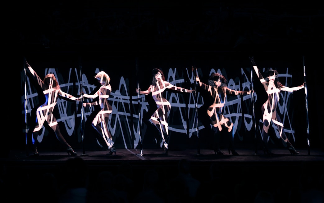 Performers on stage at Crazy Horse Cabaret Show with dynamic lighting effects.