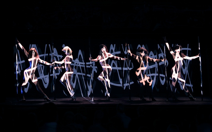 Performers on stage at Crazy Horse Cabaret Show with dynamic lighting effects.