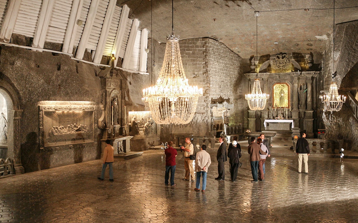 Visitors exploring the Wieliczka Salt Mine chapel with chandeliers and salt carvings.