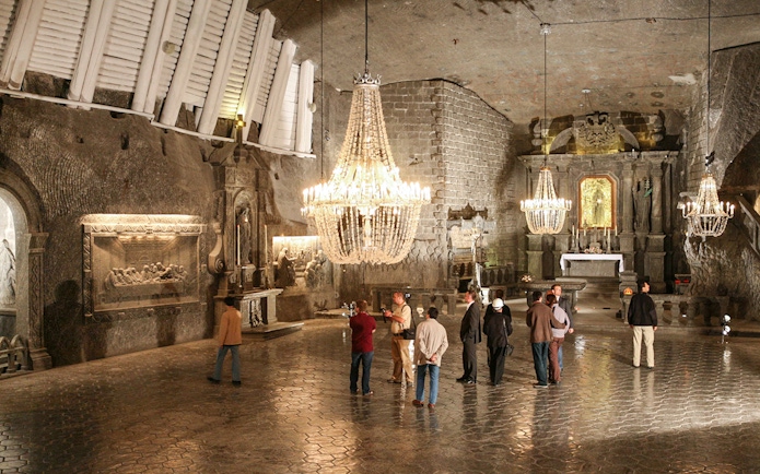 Visitors exploring the Wieliczka Salt Mine chapel with chandeliers and salt carvings.