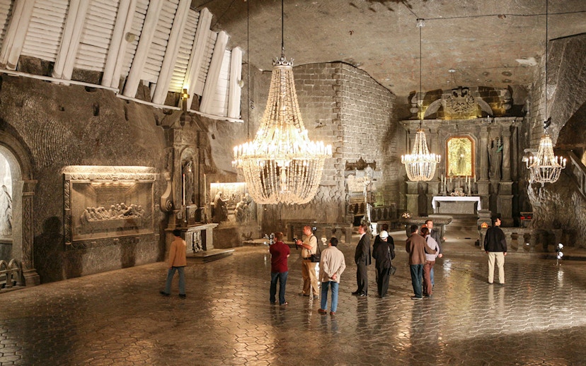 Visitors exploring the Wieliczka Salt Mine chapel with chandeliers and salt carvings.