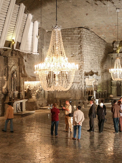 Visitors exploring the Wieliczka Salt Mine chapel with chandeliers and salt carvings.