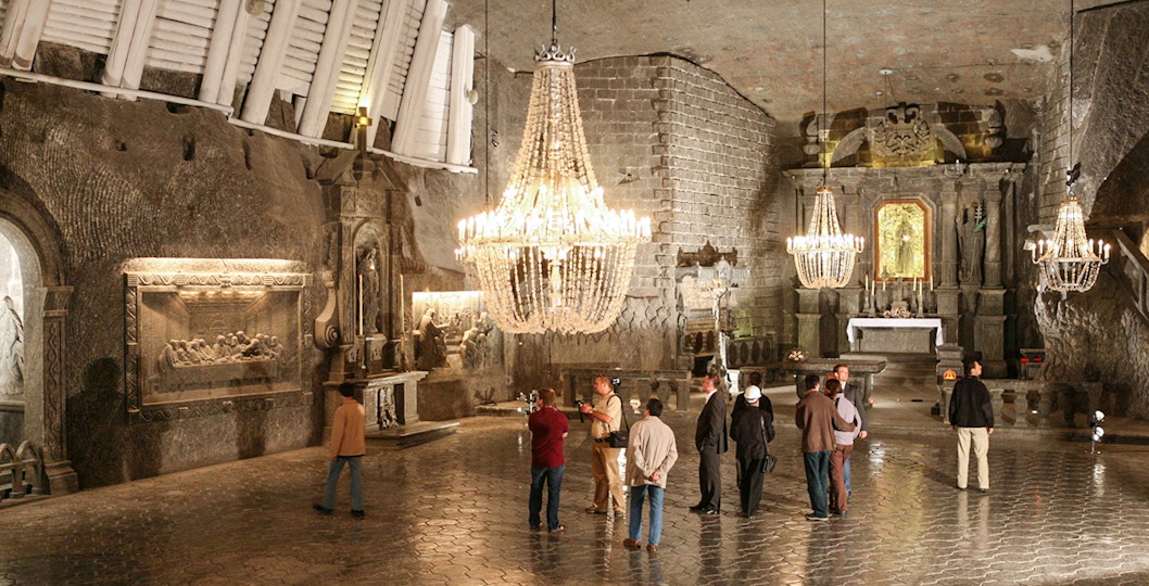 Visitors exploring the Wieliczka Salt Mine chapel with chandeliers and salt carvings.