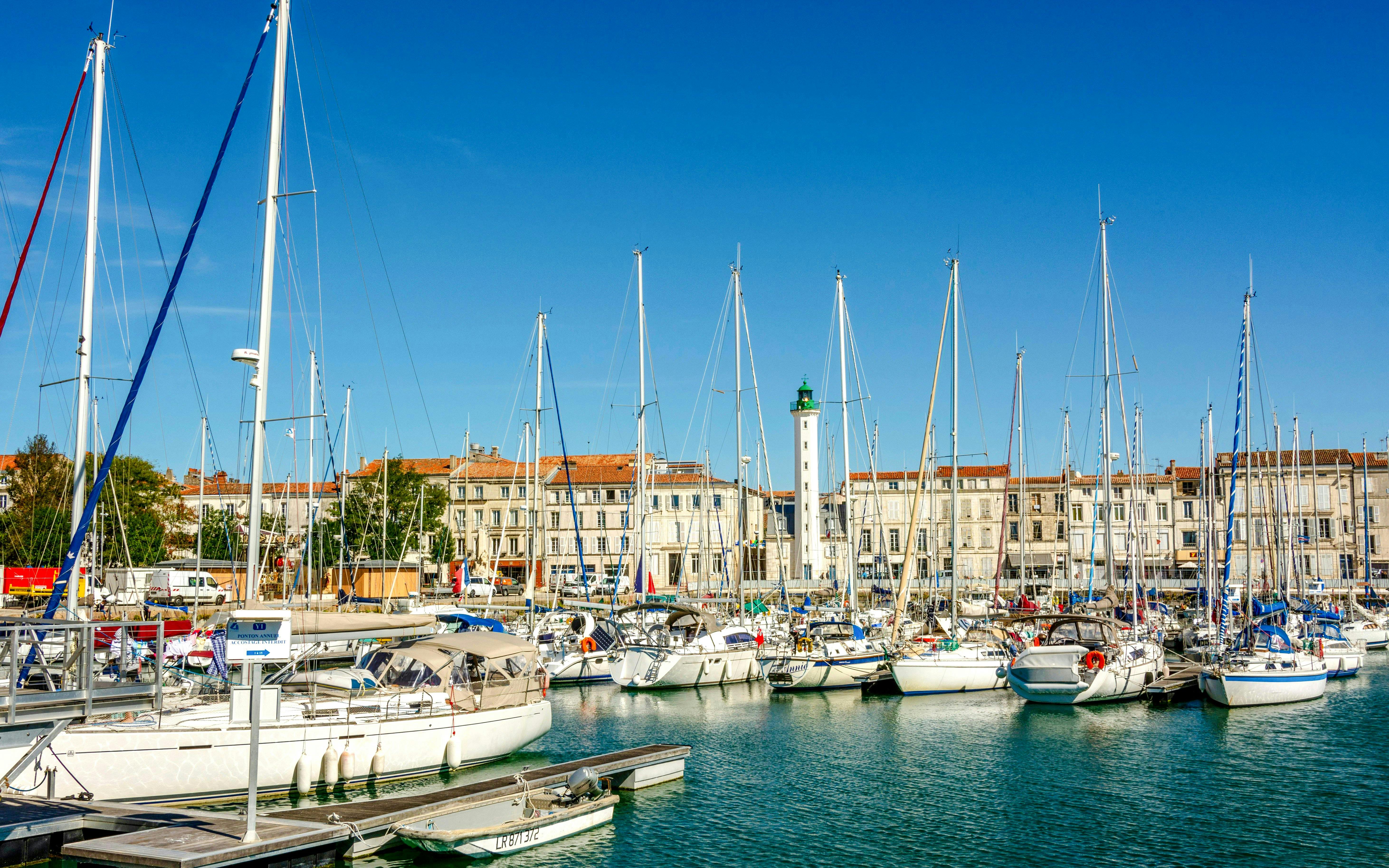 Sailboats docked at the old port of La Rochelle with historic buildings in the background.
