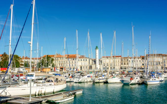 Sailboats docked at the old port of La Rochelle with historic buildings in the background.