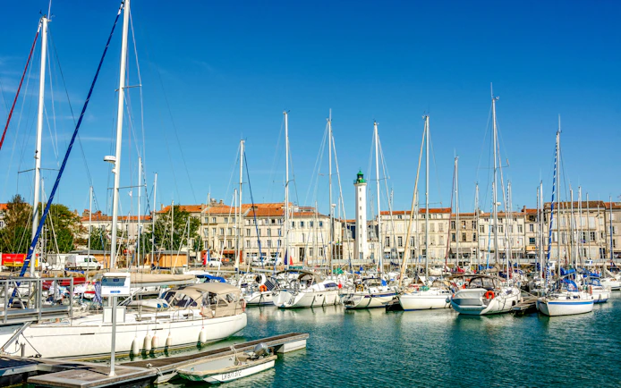 Sailboats docked at the old port of La Rochelle with historic buildings in the background.