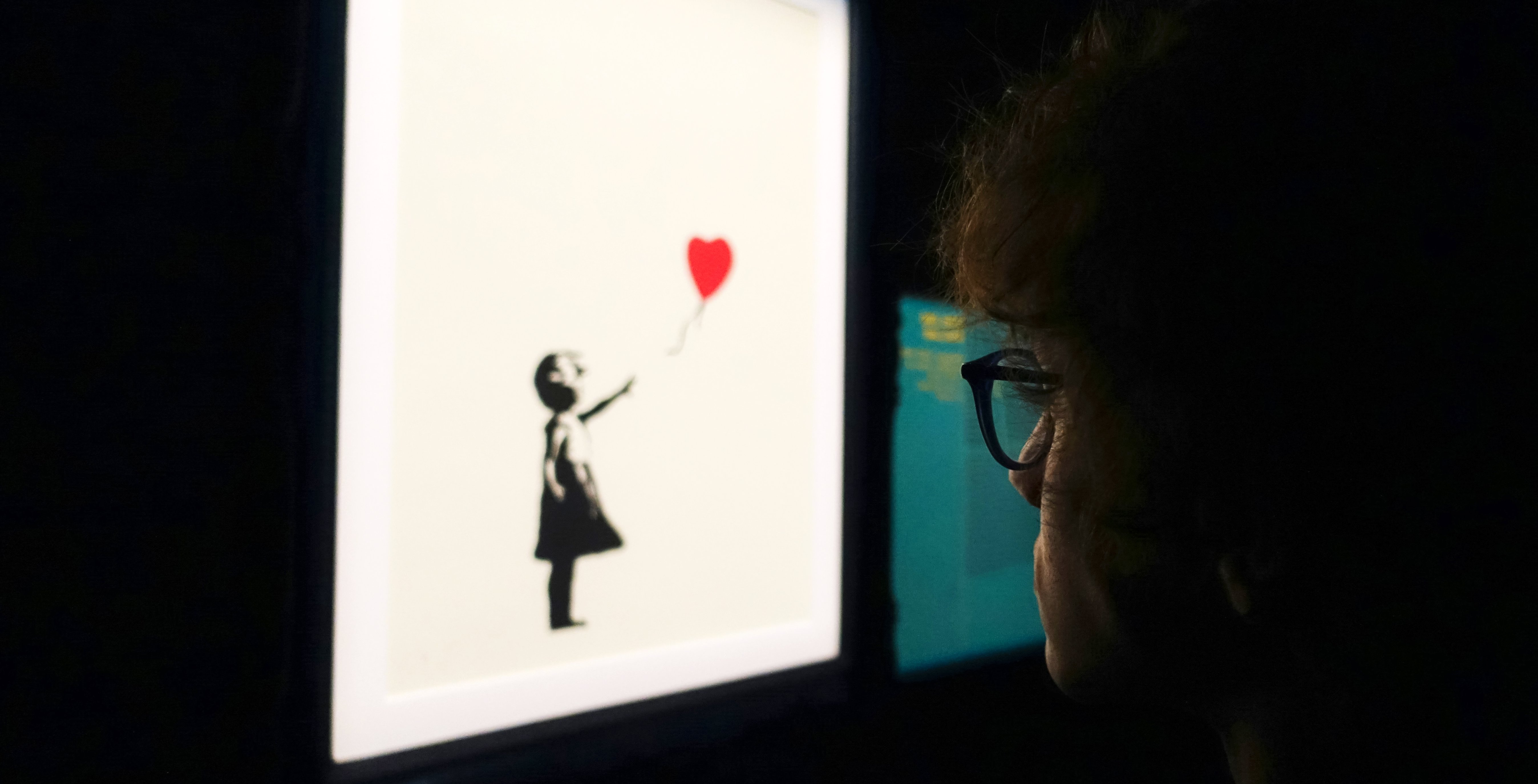 Visitor viewing Banksy's girl with balloon artwork.