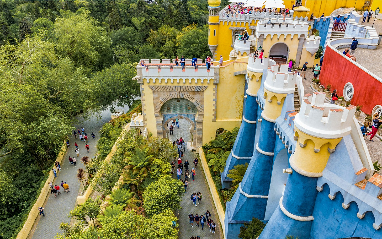 Visitors exploring the colorful architecture of the National Palace of Pena in Sintra, Portugal.