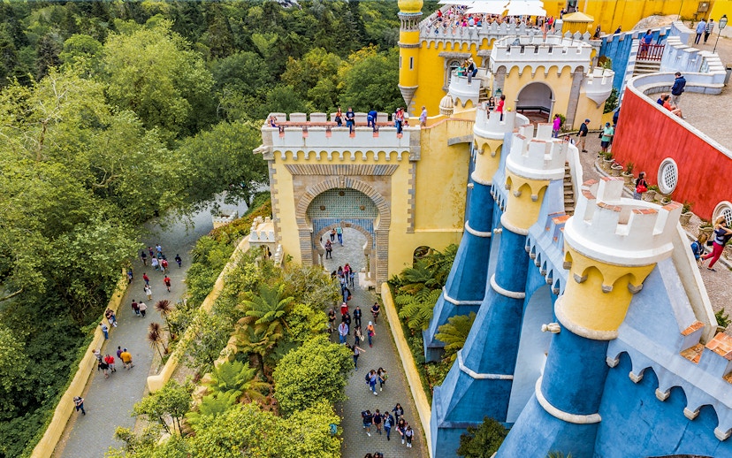 Visitors exploring the colorful architecture of the National Palace of Pena in Sintra, Portugal.
