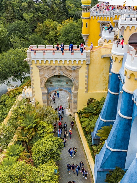 Visitors exploring the colorful architecture of the National Palace of Pena in Sintra, Portugal.