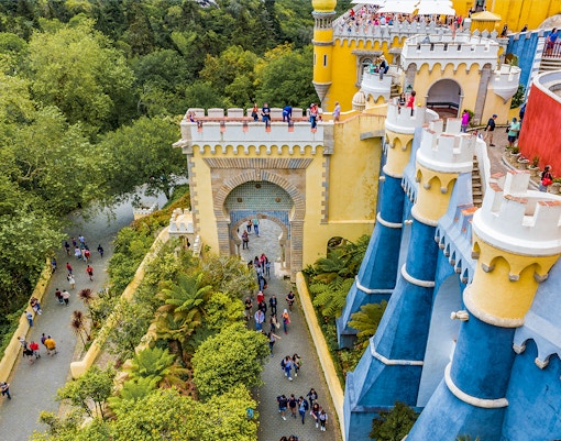 Visitors exploring the colorful architecture of the National Palace of Pena in Sintra, Portugal.