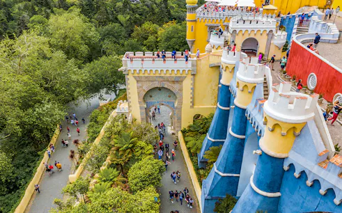 Visitors exploring the colorful architecture of the National Palace of Pena in Sintra, Portugal.