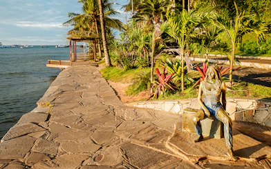 Sidewalk along Canto Beach in Buzios, Brazil with a bronze statue and ocean view.
